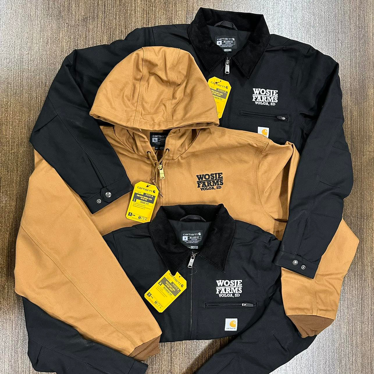 Three jackets, two black and one brown, with visible branding for business in Volga, SD