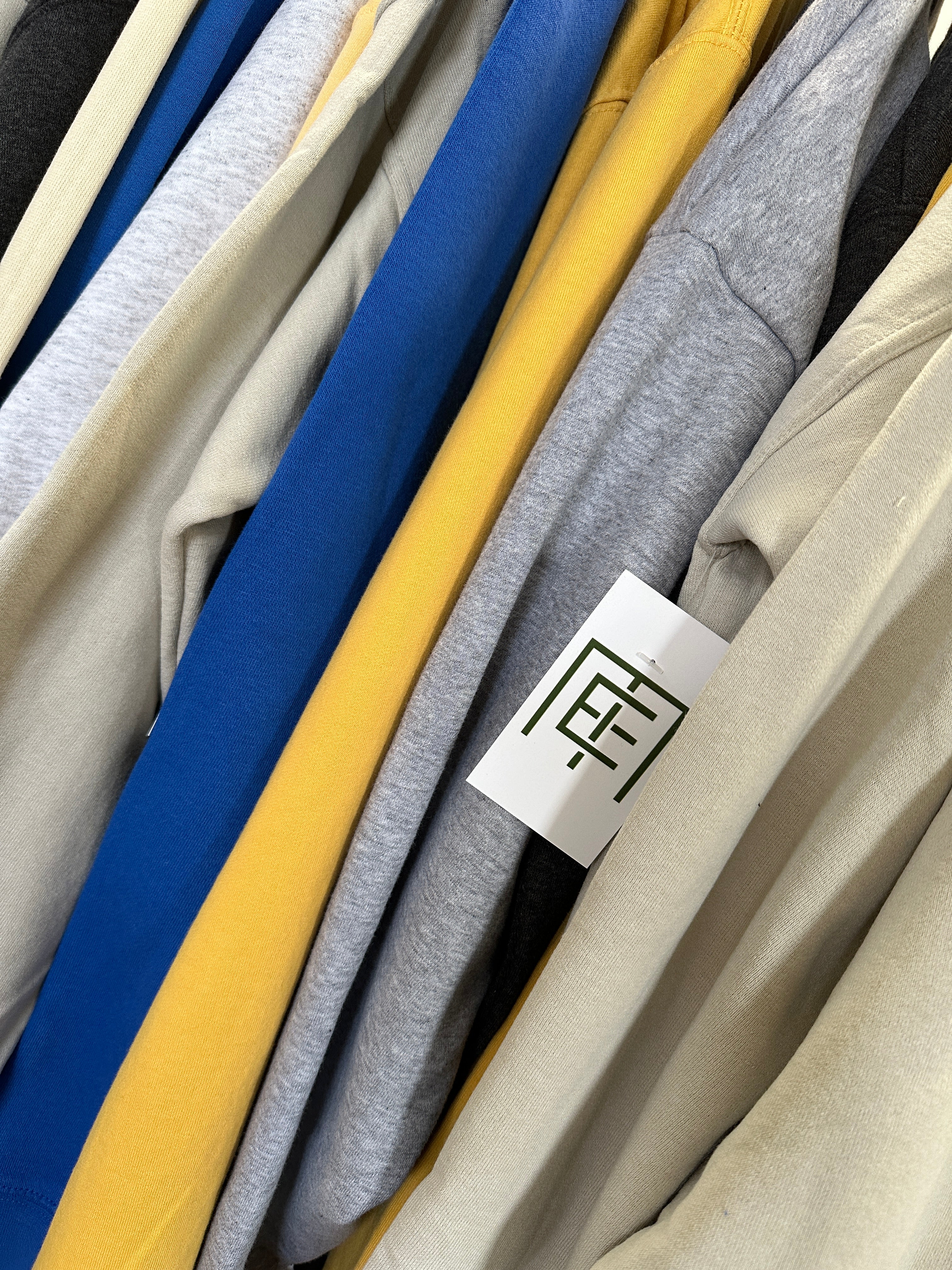 Stack of folded clothes with a brand tag on a neutral background