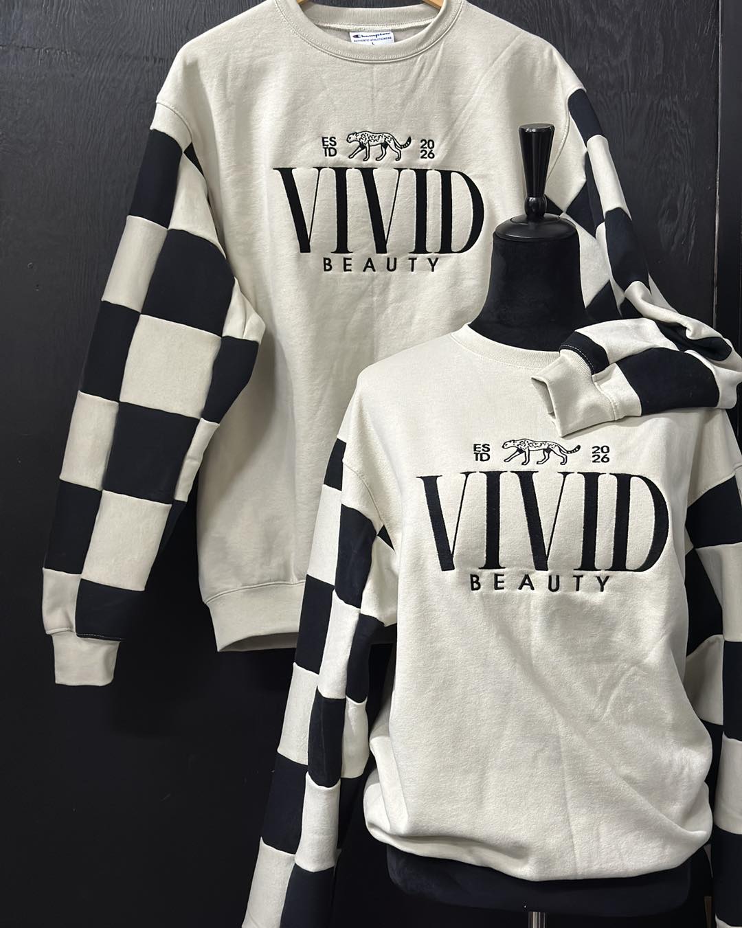 Checkered sweater with 'Vivid Beauty' text on a mannequin against a dark background