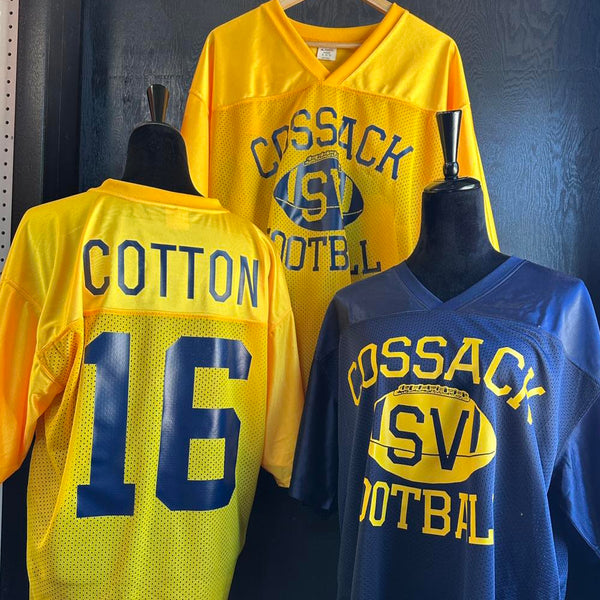 Two sports jerseys, one yellow and one blue, on mannequins with 'Cossack Football' branding made in Volga SD