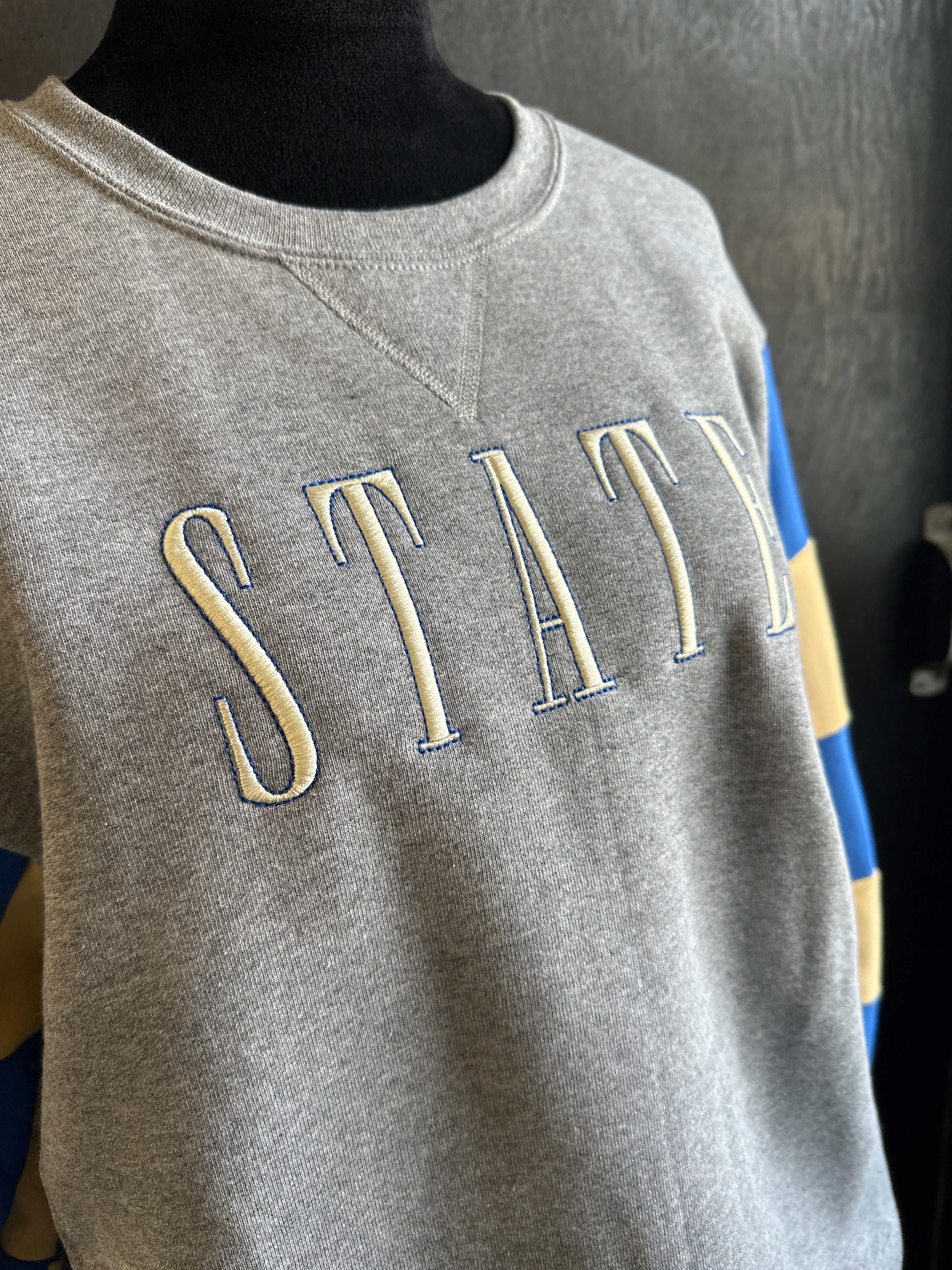 Gray sleeveless top with 'STAY' text in beige on a dark background