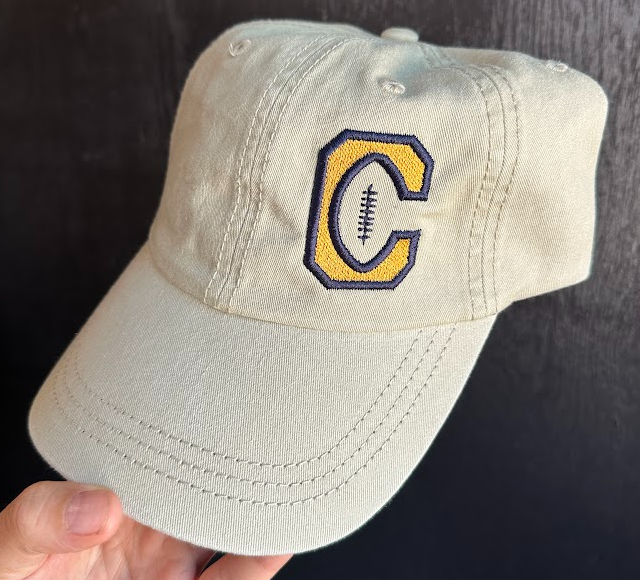 Beige cap with a logo featuring a 'C' and football icon on a dark background