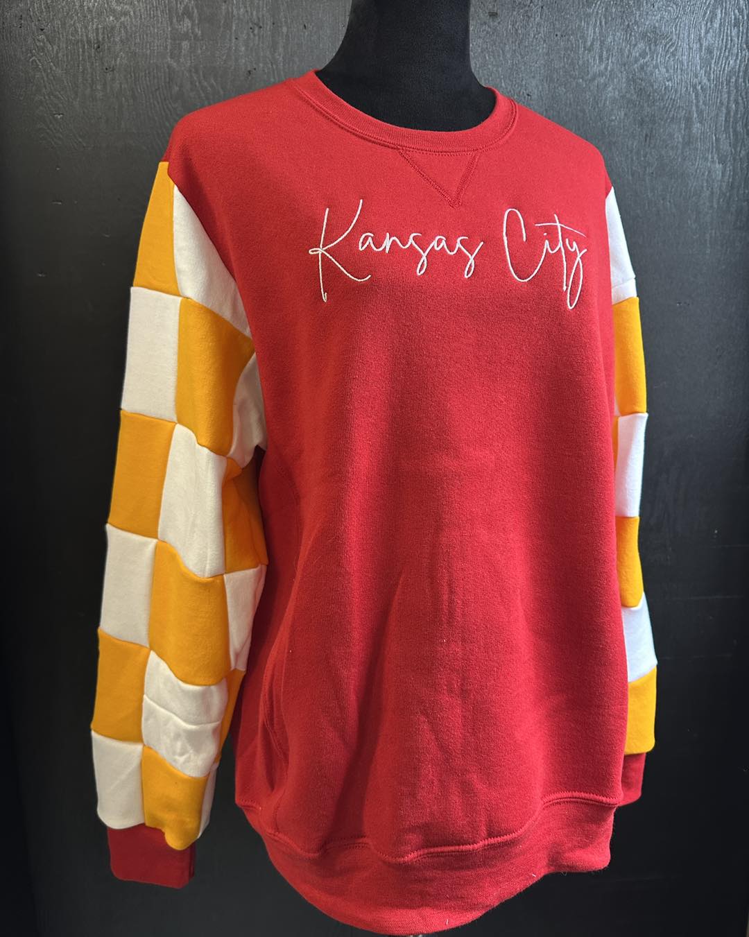 A red bodied crewneck with handmade custom checkered sleeves repurposed from other sleeves at Cotton and Customs