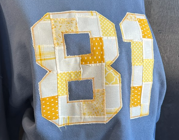 Blue sweatshirt with a large quilted number 81 design on the back.