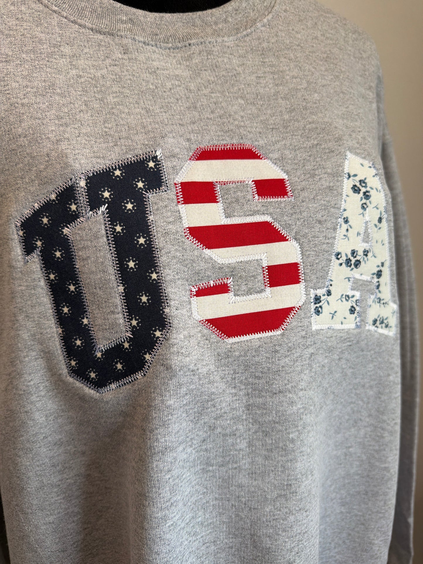 Gray sweatshirt with embroidered numbers and letters on a plain background