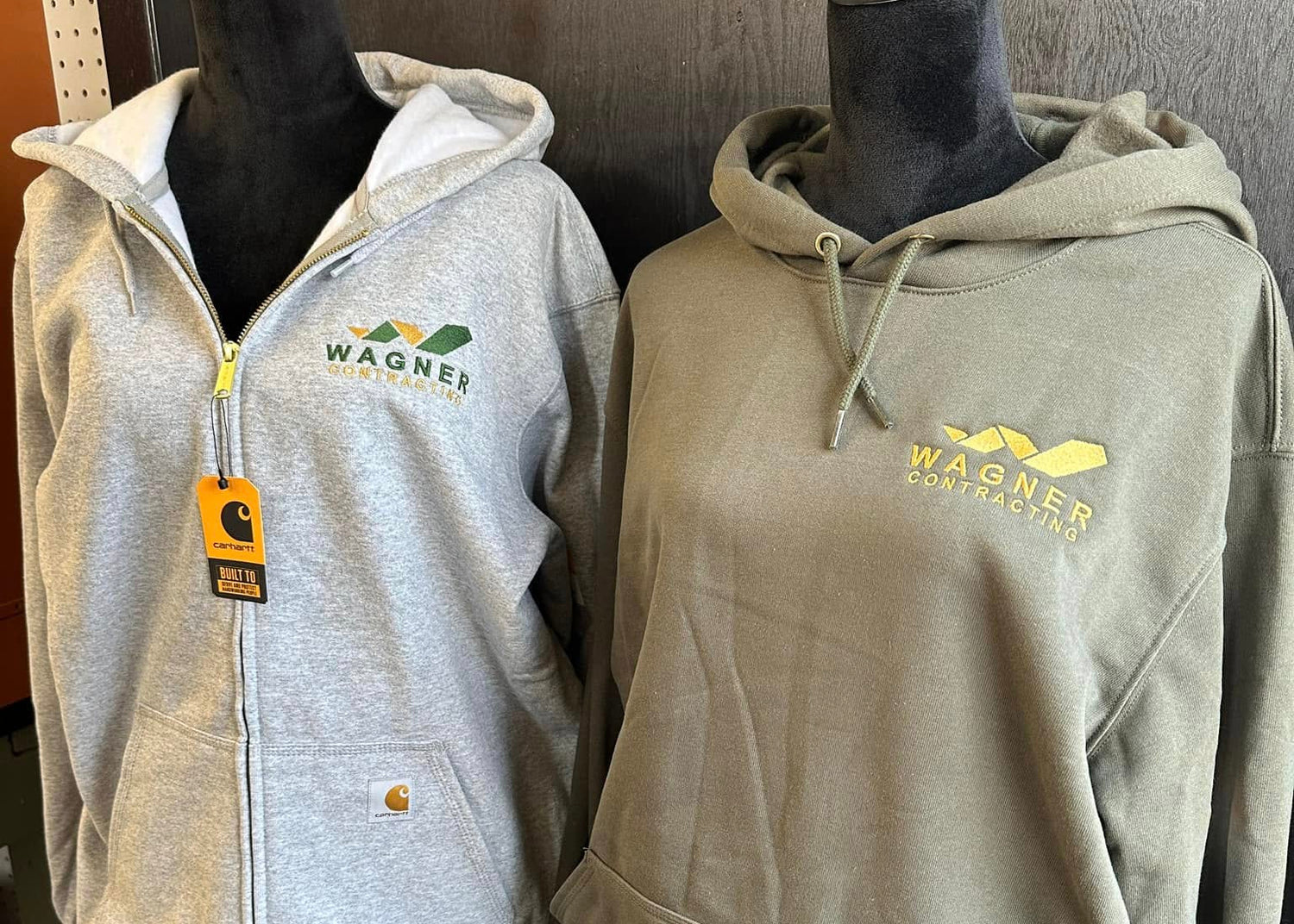 Two hoodies on mannequins with visible embroidered branding in a store setting.